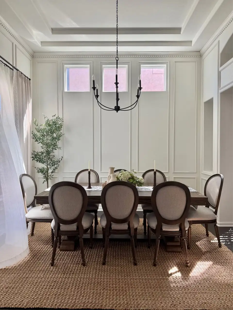 Dining room with white picture-frame wall molding, dentil crown trim and a black iron chandelier, finish work by a home remodeling company in Lochbuie, CO